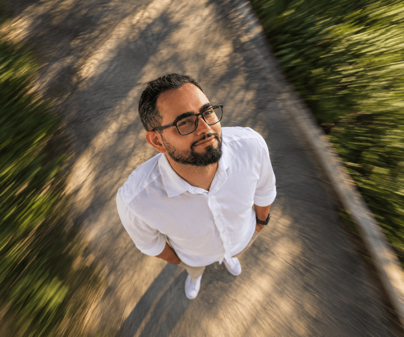 Felipe Amorim visto de cima, sorrindo, em uma estrada com a vegetação em movimento